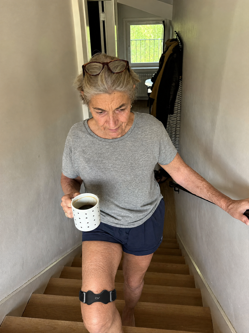 Vrouw loopt 's ochtends met koffie de trap af, met de Corevion Move onder de knie